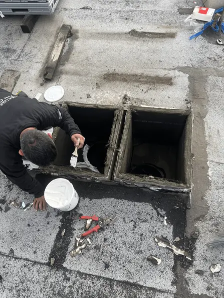 Technician sealing rooftop HVAC access during air conditioning system replacement in Sylmar